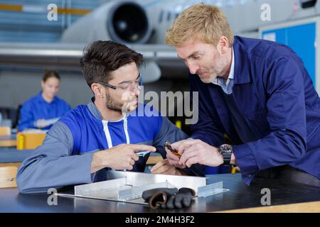 two mechanics working on a small aircraft in a hangar Stock Photo
