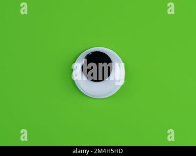 single wobbly googly eye isolated on a Lime green background with copyspace business logo Stock Photo