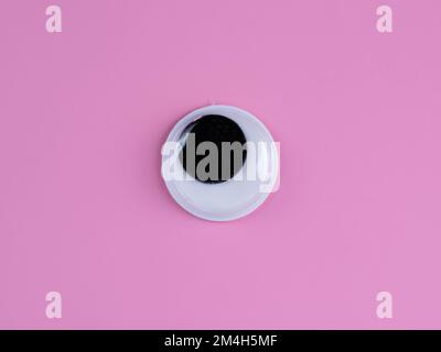 single wobbly googly eye isolated on a pink  background with copyspace business logo Stock Photo