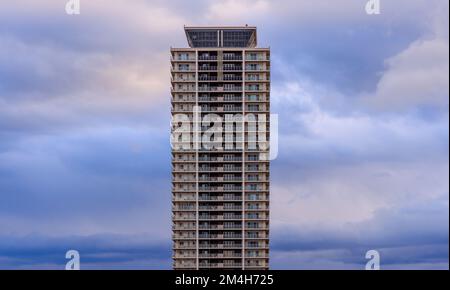Tall residential apartment building and fluffy clouds in blue hour Stock Photo