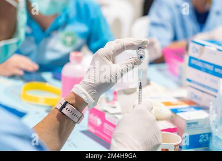 A healthcare official draws a dose from a bottle Covid-19 vaccine arranged at the vaccination center. Stock Photo