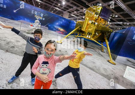 Siblings from CheongHH family (front left to right) Alex (9-year-old), Alice (8-year-old) and Alan (10-year-old) pose in front of a model in InnoTech Expo at Hong Kong Convention and Exhibition Centre in Wan Chai. The first day open to public. 12DEC22.      SCMP / May Tse Stock Photo