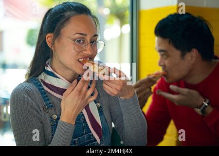 Diverse team worker having pizza together in an office cafeteria. Cheerful workers staff sharing meal. Enjoying and having fun at lunch break. Co-work Stock Photo