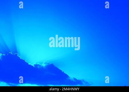 Sunbeams above the clouds.Sun shining through the clouds with sunbeams. Beautiful blue sky with sunbeams and clouds. The rays of light shine. Stock Photo