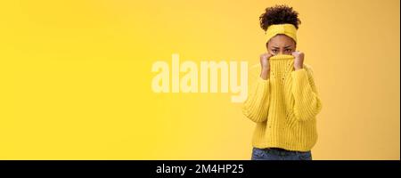 Cute upset scared timid insecure african-american offended girl hiding face pulling sweater collar nose frowning pouting look sorrow insulted afraid Stock Photo