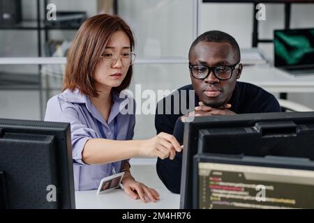 Multiethnic couple of developers working on computer together to develop new program Stock Photo