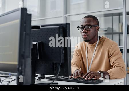 African American programmer in eyeglasses concentrating on his online work on computer, he typing computer codes Stock Photo
