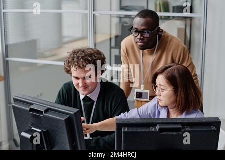 Group of young IT programmers working with codes on computers in team Stock Photo