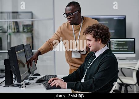 Two young colleagues developing new code for computer program in team in modern office Stock Photo