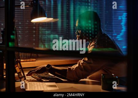 African American programmer concentrating on his work on computer he working overtime in dark office Stock Photo