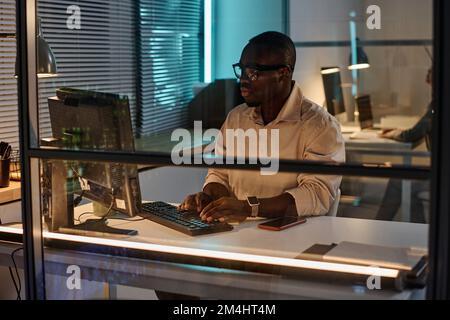 African American businessman concentrating on his work on computer during his work in dark office Stock Photo