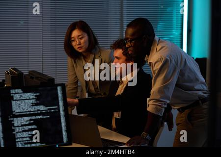 Group of developers working with computer codes on computer in team till late at night Stock Photo