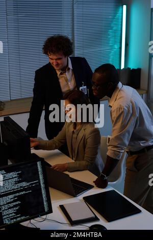 High angle view of team of programmers developing new program on computer during their work in office till late at night Stock Photo