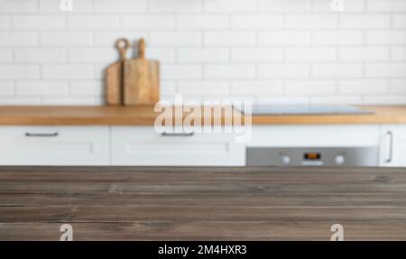 Dark wooden countertop with free space for mounting a product or layout against the background of a blurred white kitchen  with cutting board. Horizon Stock Photo