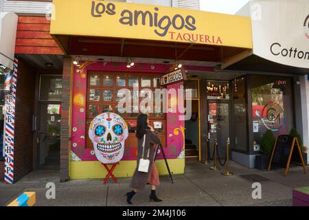 Woman walking past colorful facade of  Los Amigos Taqueria Mexican restaurant on Davie Street in the West End, Vancouver, BC, Canada Stock Photo