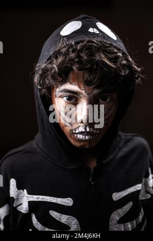 Halloween portrait of child with face painted by Jack-o'-lantern. Face close up isolated on black background Stock Photo