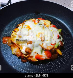Making a mini tortilla mozzarella combination pizza in the pan Stock Photo