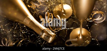 new years eve. luxury gold champagne bottle with glasses and golden ribbons on black background. banner Stock Photo