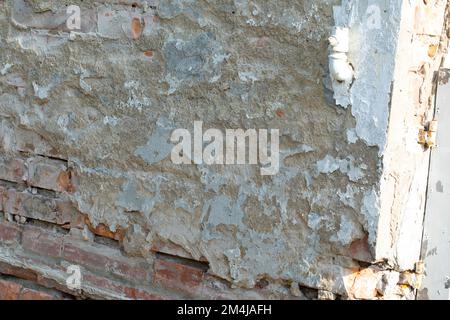 Decaying wall of a house under renovation. Crumbling plaster and broken stones. Grunge style degradation image. Stock Photo