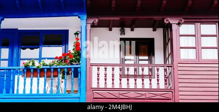 Blue balcony with flowers pots and pink balcony. Tazones, Principality of Asturias, Spain, Europe Stock Photo