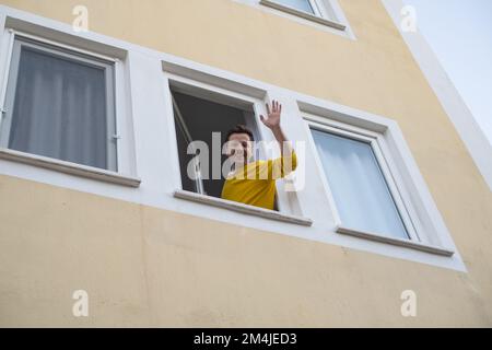 Mature man waving hand greeting his friend from window. Stock Photo