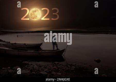 Man watching the bear from the boat by the lake. full moon at top of sky and number 2023 abstract background. Happy new year and holiday concept Stock Photo