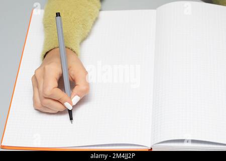 Hand of woman who is about to write on an empty page of notebook with a black marker. Large copyspace and space to add advertising text Stock Photo