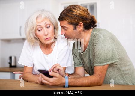 Relaxed mature couple using phone at home Stock Photo