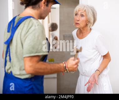 Elderly woman talking with plumber at home Stock Photo