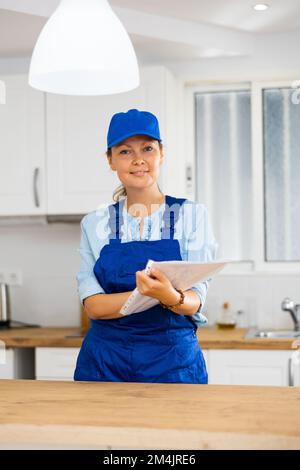 Woman house cleaner making notes in kitchen Stock Photo