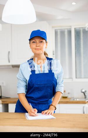 Woman house cleaner making notes in kitchen Stock Photo