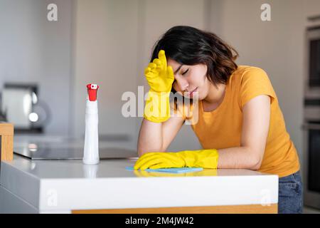 Young Arab Woman Feeling Tired While Making Cleaning In Kitchen Stock Photo
