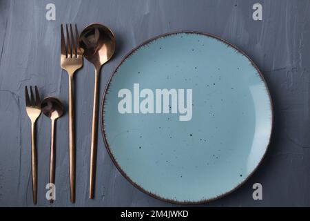 set table. Spoon fork and plate stands on a gray background with a place for food and text copyspace Stock Photo