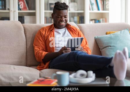 Smiling african american guy using digital pad at home Stock Photo