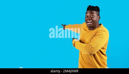 Look There. Amazed Black Man Pointing At Copy Space Behind Him Stock Photo