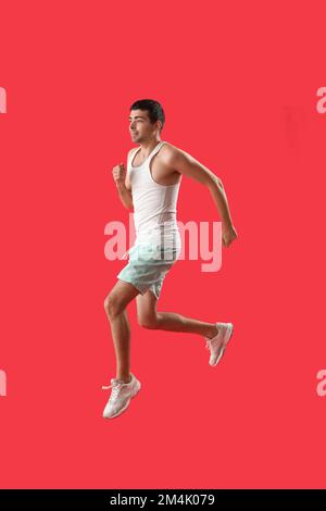 Sporty young man jumping on red background Stock Photo