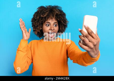 Emotional young black woman holding cell phone and exclaiming Stock Photo