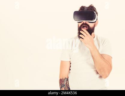 Man with beard in VR glasses, white background. Guy with head mounted display interact in virtual reality. Hipster on shocked face exploring virtual Stock Photo