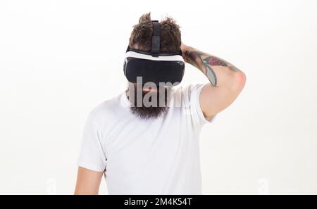 A person in virtual glasses flies in room space. Portrait of bearded male in a white T-shirt with virtual reality glasses on his head isolated on