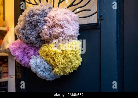 Christmas wreath of large multi-colored paper and rag balls in pastel colors on the door Stock Photo