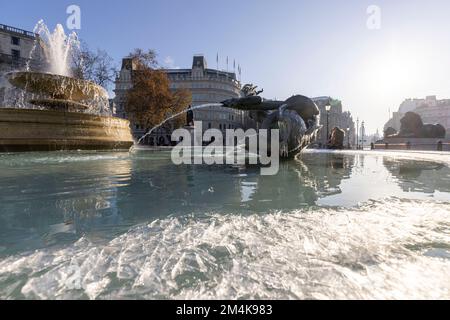 Trafalgar Square fountain remains frozen well into the morning. People have fun with chunks of ice on the fountain.   Image shot on 16th Dec 2022.  ©B Stock Photo