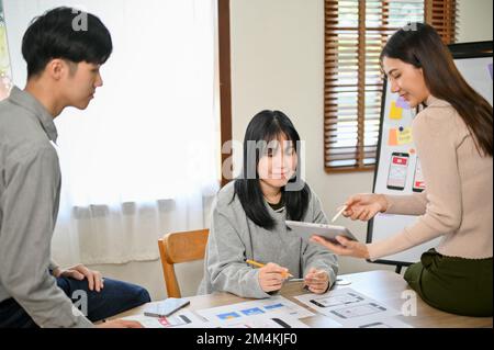 A group of millennial Asian graphic designers is meeting to discuss and plan the color scheme for a new mobile application interface design.  UX UI bu Stock Photo