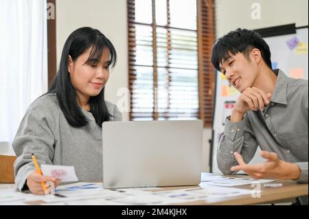 Professional millennial Asian male and female designers are working together, discussing and designing their mobile application interface. Stock Photo
