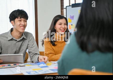 Happy and cheerful millennial Asian business team startup in the meeting with developer and graphic designer for develop a new mobile application. Stock Photo