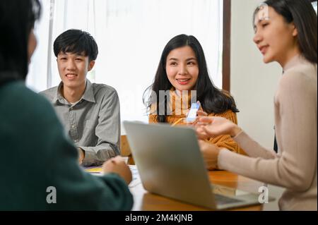 Attractive and charming Asian female mobile application designer presenting and sharing her ideas to her team during the meeting. UX UI concept Stock Photo