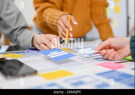 close-up image, A professional female graphic designer pointing her pen on paper, discussing and brainstorming a new prototype with her team. Stock Photo