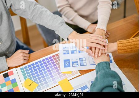 Top view, Team of UX developers and UI designer putting their hands together, meeting and brainstorming their new application. Stock Photo