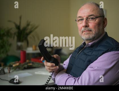 Berlin, Germany. 12th Dec, 2022. Pastoral counselor Uwe Müller from the Church Telephone Counseling Service in Berlin and Brandenburg sits by the phone in an office of the Diakonie Volunteer Center. The demand for telephone counselling is particularly high at Christmas. (to dpa Telefonseelsorge seeks volunteers - increasingly difficult) Credit: Jens Kalaene/dpa/Alamy Live News Stock Photo