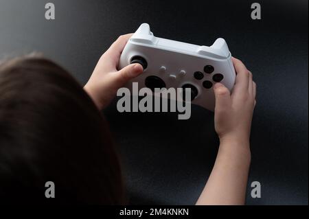 Kid hold white game joystick on black background Stock Photo