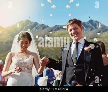 Love is in the air. a cheerful young bride and groom walking hand in hand together after the wedding reception. Stock Photo